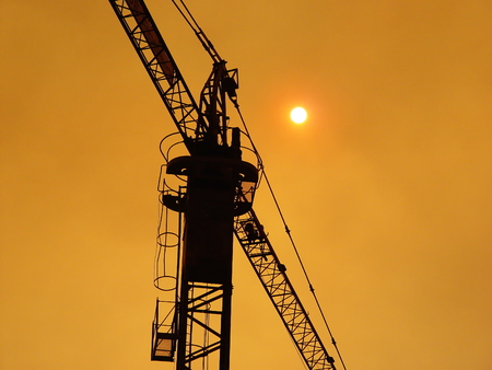 Crane silhouette over an oranje sky and a timid sun. This photo was taken during a fire.の写真素材