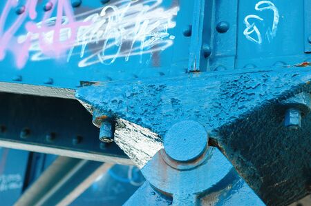 Old textured bridge bearing painted in blue and some grafitties over the blue paintの写真素材