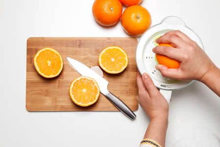 hand chopping a orange in a chop-board and squeezerの写真素材