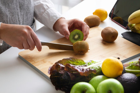 Hands cutting kiwi and more fruit on a cutting boardの写真素材