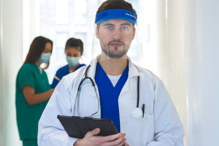 portrait of a doctor with a mask and two doctor on the back of the corridorの写真素材