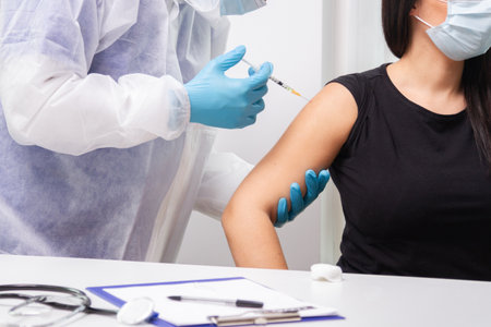 doctor with a syringe injecting on the shoulder a woman the vaccineの写真素材