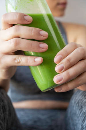 attractive woman showing her green smoothie to the cameraの写真素材
