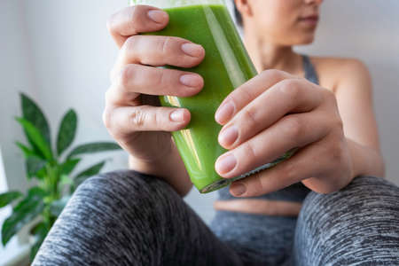 attractive woman showing her green smoothie to the cameraの写真素材