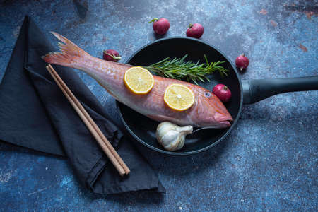still life a fish on a pan with lemon and garlic with background