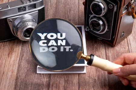 two cameras and magnifying glass are on wooden table with a bookの写真素材