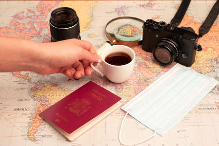 a hand grabbing a cup of coffee with a map and camera as a backgroundの写真素材