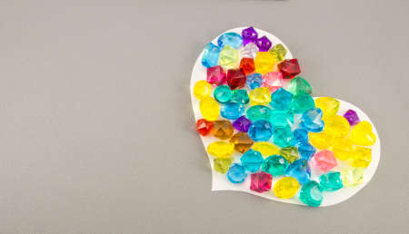 gems and white paper heart on gray backgroundの写真素材