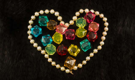 White pearl heart with color gems within on black fur backgroundの写真素材