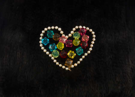 White pearl heart with color gems within on black fur backgroundの写真素材