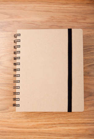 Recycled paper notebook with black elastic band on wooden の写真素材