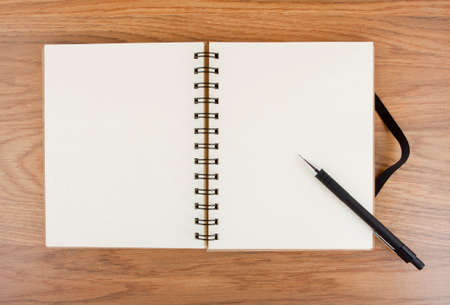 Opened notebook with black elastic band and pencil on a table.の写真素材