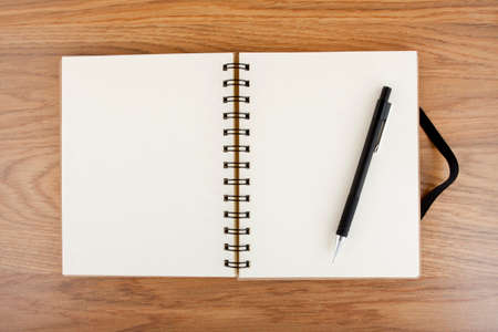 Opened notebook with black elastic band and pencil on a table