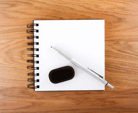 Open empty notebook with pen and eraser on a wooden 