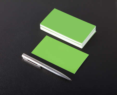 green blank business cards with pen on a black leather backgroundの写真素材