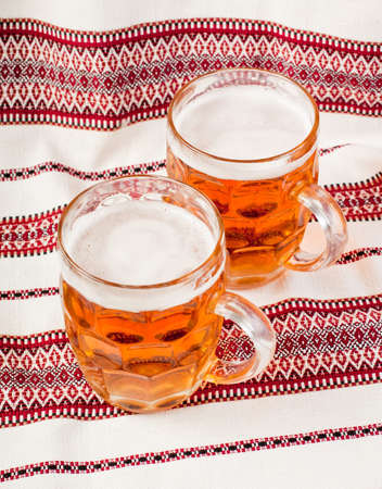 A glass of beer on the table. A glass of beer glass on the tablecloth. A glass of dark beer. A glass of beer on a patterned tableclothの写真素材