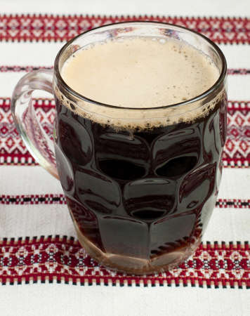 A glass of beer on the table, Glass of dark beer glass on the tablecloth, A glass of dark beer, Black beer on rushnyk, A glass of beer on a patterned tableclothの写真素材