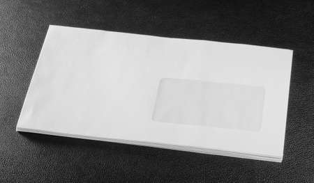 white envelope on black leather backgroundの写真素材