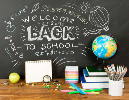 Back to school concept with writing on blackboard and desk, apple, books, stationery