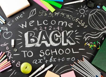 Back to school handwritten with school supplies on a black background. Top view.