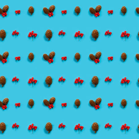 Top view of lines from cones and rowan berries on a blue background. Christmas seamless pattern