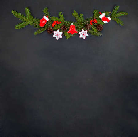 Christmas floral decoration with toys, holly berry, pine cones and winter greenery over chalkboard....