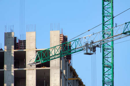Tower crane at the construction site against the blue sky