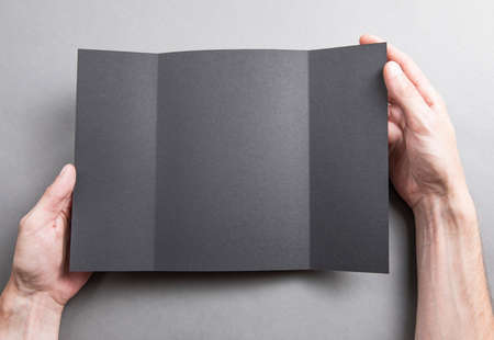 Mens hands holding empty black booklet on gray background. View from aboveの写真素材