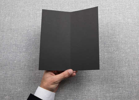 Mens hands holding empty black booklet on gray background. View from aboveの写真素材