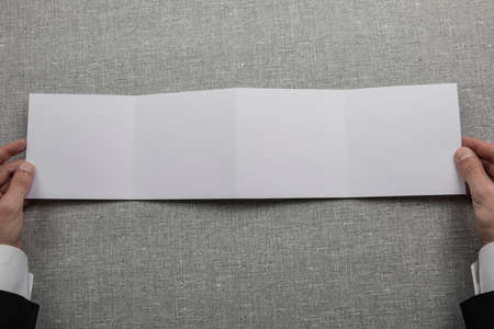 Mens hands holding empty white booklet on gray background. View from aboveの写真素材