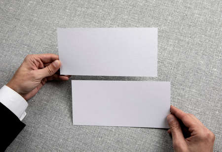 Mens hands holding empty white flyers on light gray background. Blank paper mock-upの写真素材