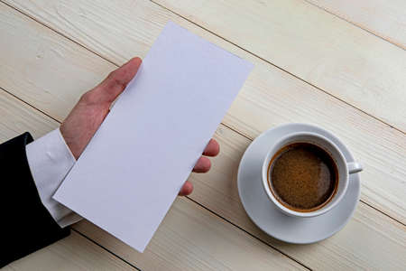 Mens hand holding empty white flyer on wooden backgroundの写真素材