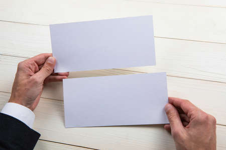 Mens hands holding empty white flyers on wooden backgroundの写真素材