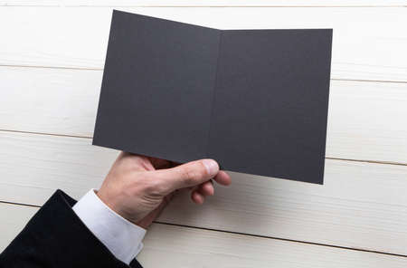 Mens hands holding empty black booklet on gray background. View from aboveの写真素材