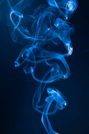 Abstract blue smoke swirls on dark backgroundの写真素材