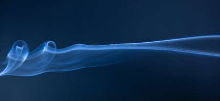 Abstract blue smoke swirls on dark backgroundの写真素材