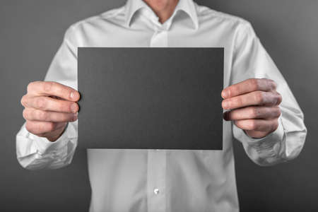 A man in a white shirt holding a black booklet