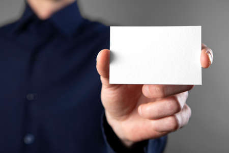 A man in a blue shirt holding a white business cardの写真素材