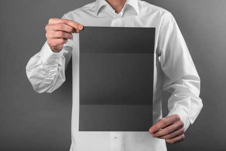 A man in a white shirt holding a black bookletの写真素材