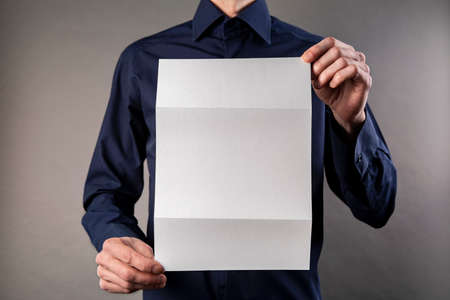 A man in a blue shirt holding a white booklet