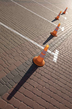 Orange traffic cones standing in a row near the parkingの写真素材