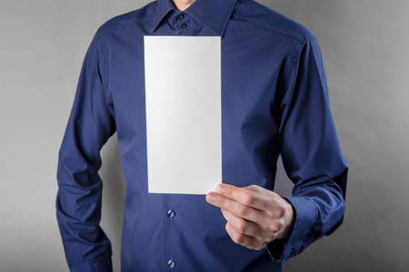 A man in a blue shirt holding a white bookletの写真素材