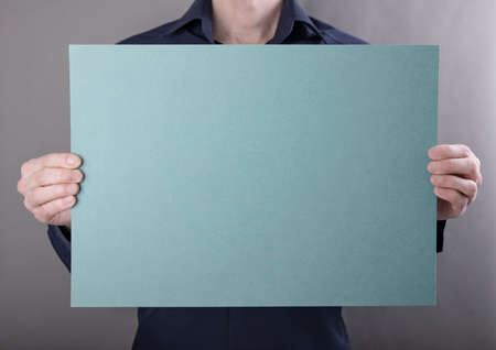 A man in a blue shirt holding a blue posterの写真素材