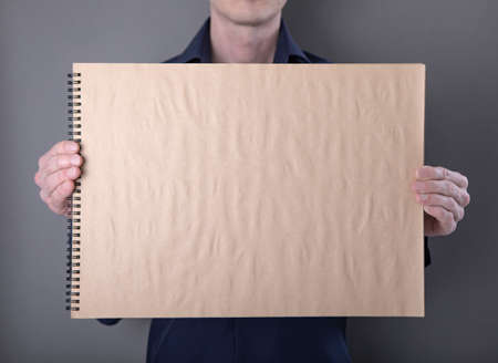 A man in a blue shirt holding a notebook