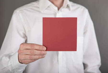 A man in a white shirt holding a red note paperの写真素材