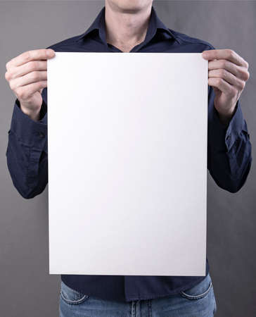 A man in a blue shirt holding a white poster