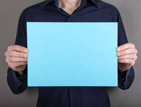 A man in a blue shirt holding a blue letterheadの写真素材