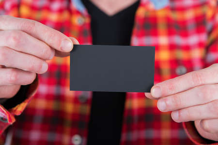 A man in a colored shirt holding a black business card