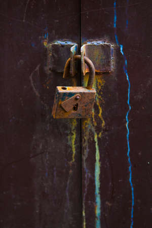 Old iron padlock on locked closed door.