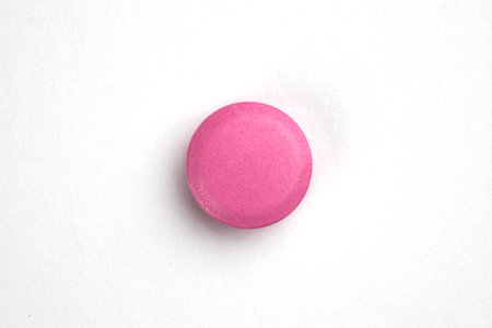 Pink round pill on white background. Health care concept
